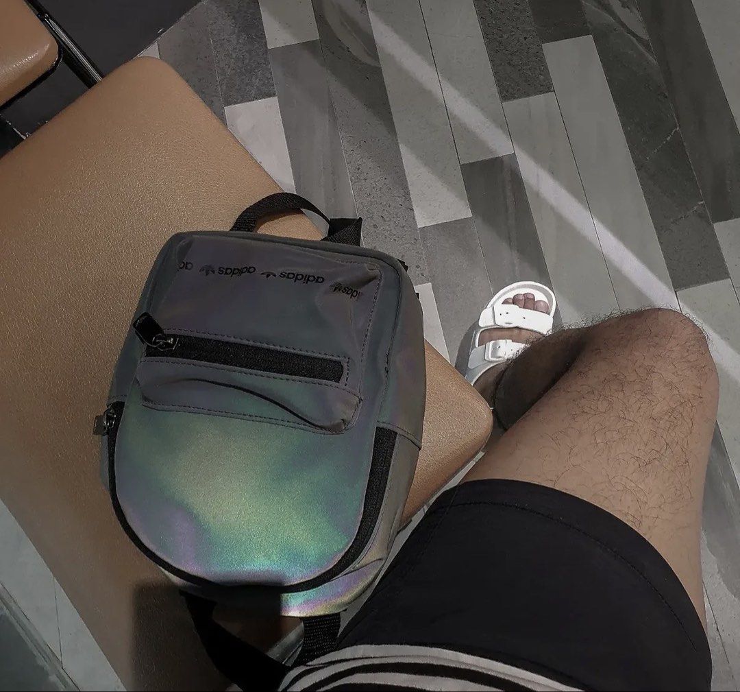Adidas Holographic Mini Backpack Grey (Category: Backpacks) located in Las Pinas. Submitted by iamdaverybest (Listing ID 1466652590, Image 1). Description: - Brand: Adidas - Style: Mini backpack - Color: Grey holographic (shifts to rainbow colors in the light) - Features: Front zip pocket and adjustable black straps - Size: Compact, perfect for daily essentials - Condition: Used, as seen in photos.