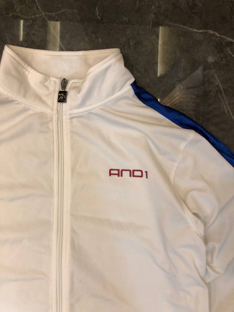 AND1 Vintage Track Jacket White Red Blue Size M (Category: Coats, Jackets and Outerwear) located in Santa Cruz. Submitted by remsonnnc (Listing ID 1466623068, Image 2). Description: - Brand: AND1 - Color: White with red and blue side stripes - Size: Medium (made in Taiwan) - Details: Full zip, custom logo zipper pull, red chest embroidery, and large back logo graphic - Condition: Good pre-loved condition with a small stain on the inner collar - P