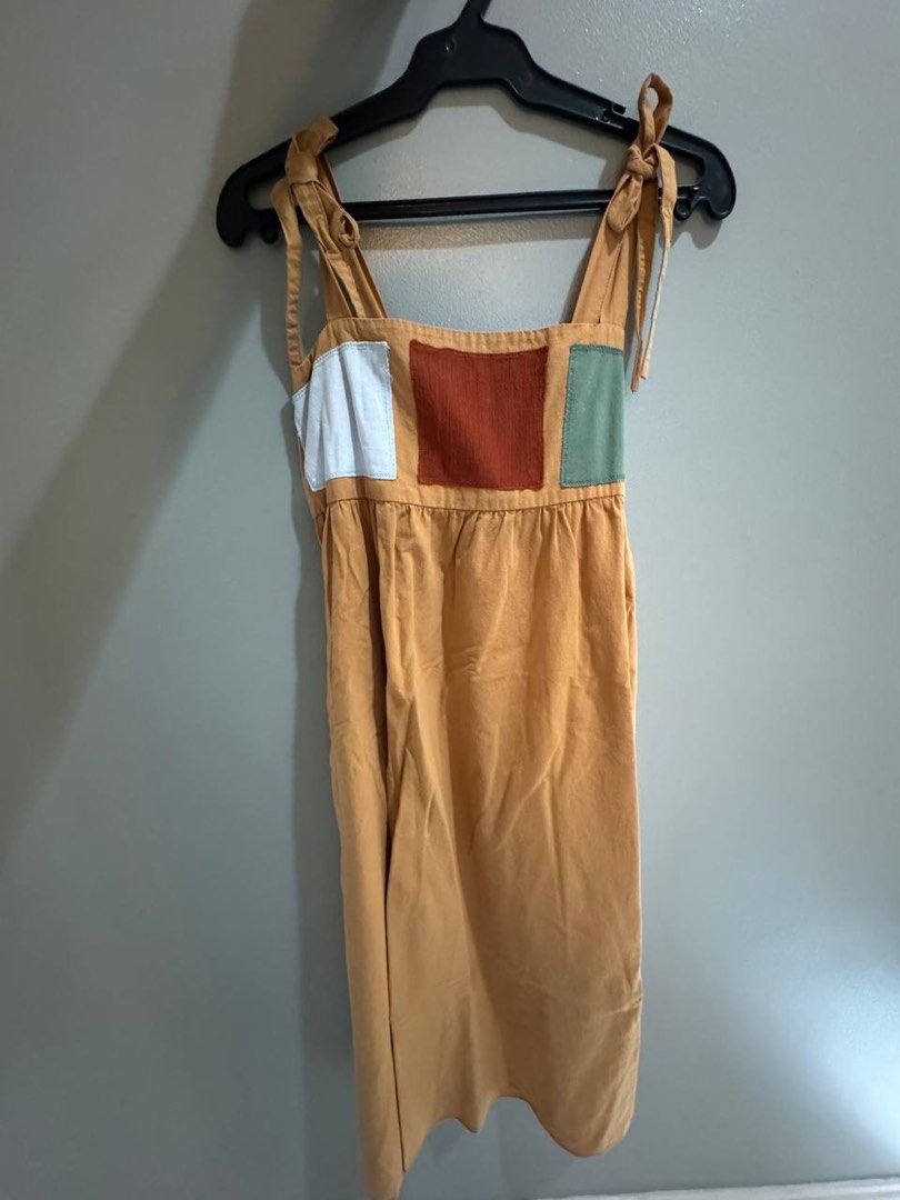 Anika Mustard Yellow Patchwork Midi Dress Size M (Category: Dresses) located in Taguig. Submitted by anxmz (Listing ID 1466605515, Image 1). Description: - Brand: Anika - Size: Medium (M) - Color: Mustard yellow with colorful square patches - Neckline/Straps: Square neck with adjustable tie-up shoulder straps - Fit: Gathered waist for a flowy, flattering silhouette - Material: Soft, breathable, and comfortable for warm weather.