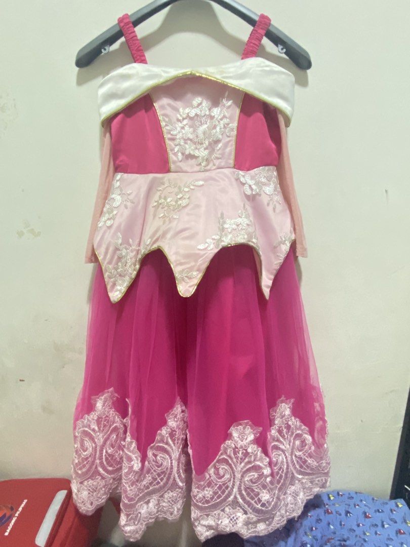 Aurora Inspired Dress (Category: Babies & Kids Fashion) located in Las Pinas. Submitted by dhyn29 (Listing ID 1466677956, Image 1). Description: - Style: Pink princess dress with gold trim - Design: White off-shoulder collar and floral lace overlay on the bodice peplum and hem - Sleeves: Thin pink mesh sleeves (Note: slight pilling on mesh, see close-up photo) - Closure: Convenient back zipper - Condition: Pre-loved, well-maintained With minor fl