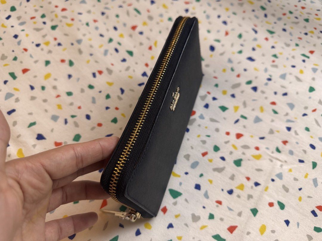 Authentic Kate Spade New York black zip-around wallet (Category: Wallets & Card holders) located in Makati City. Submitted by lpcalundan (Listing ID 1466566466, Image 2). Description: - Brand: Kate Spade New York - Material: Black textured leather with gold-tone hardware and front logo - Closure: Zip-around with pull tab - Exterior: Convenient back slip pocket - Interior: Chic black-and-white striped lining, multiple card slots, bill compartments