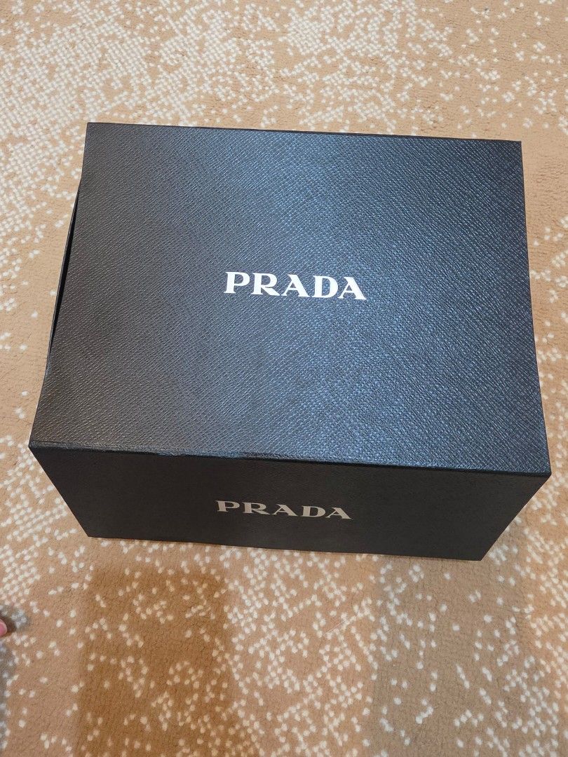 Authentic Prada Black Gift Box Saffiano Texture (Category: Luxury Bags & Wallets) located in Makati City. Submitted by berean87 (Listing ID 1466732067, Image 1). Description: - Authentic Prada textured cardboard box - Classic black exterior with white logo lettering - Dimensions: approx. 24 cm x 18 cm - Includes clean black shredded paper packaging - Excellent, clean condition - perfect for gifting or luxury storage.