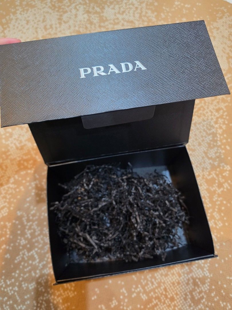 Authentic Prada Black Gift Box Saffiano Texture (Category: Luxury Bags & Wallets) located in Makati City. Submitted by berean87 (Listing ID 1466732067, Image 3). Description: - Authentic Prada textured cardboard box - Classic black exterior with white logo lettering - Dimensions: approx. 24 cm x 18 cm - Includes clean black shredded paper packaging - Excellent, clean condition - perfect for gifting or luxury storage.