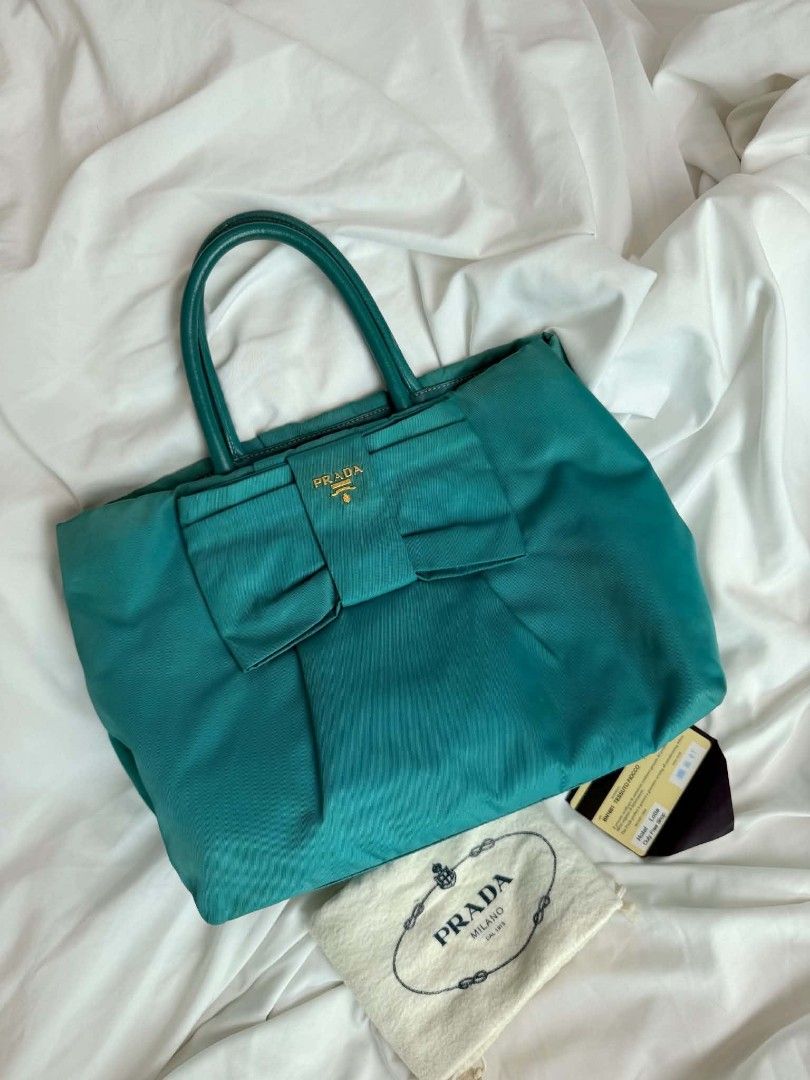 Authentic Prada Tessuto Fiocco Teal Nylon Bow Tote Bag (Category: Luxury Bags & Wallets) located in Marikina City. Submitted by aussiemaan (Listing ID 1466631508, Image 1). Description: Prada Tessuto Fiocco tote in a teal green shade. Nylon body with matching leather handles and trim. Large statement bow on the front with gold-tone Prada logo lettering. Magnetic snap closure on top, zip pocket inside. Signature patterned lining. Bottom feet for p