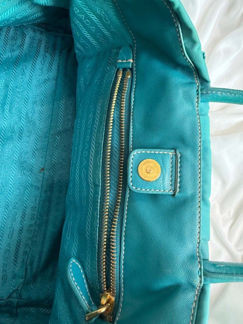 Authentic Prada Tessuto Fiocco Teal Nylon Bow Tote Bag (Category: Luxury Bags & Wallets) located in Marikina City. Submitted by aussiemaan (Listing ID 1466631508, Image 3). Description: Prada Tessuto Fiocco tote in a teal green shade. Nylon body with matching leather handles and trim. Large statement bow on the front with gold-tone Prada logo lettering. Magnetic snap closure on top, zip pocket inside. Signature patterned lining. Bottom feet for p