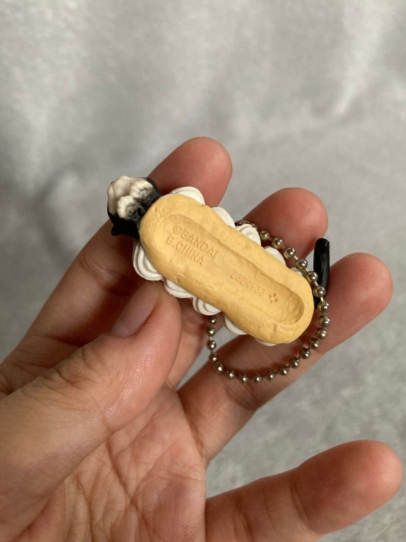 Bandai Neko Cafe 6 Cat Eclair Pastry Keychain (Category: Character Goods) located in Rizal. Submitted by sheeraay (Listing ID 1466650268, Image 3). Description: - 100% Authentic Official Bandai Gachapon - Adorable tuxedo cat hiding inside a pink-glazed eclair with cream filling - Comes with a sturdy metal ball chain for easy attachment - Authenticated with official Bandai copyright and China production stamps on the bottom - Compact and lightweig