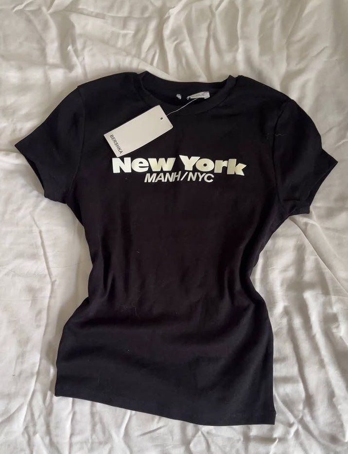 Bershka Black New York Top (Category: Shirts) located in Cavite. Submitted by bunniirai (Listing ID 1466714738, Image 1). Description: - Brand: Bershka - Size: Small - Condition: Brand new with tag attached - Fit: Fitted cut with short sleeves DM me for more details. STRICTLY PAYMENT FIRST..