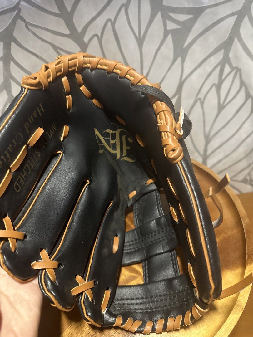 Black and Tan Handcrafted Nylon Stitched Baseball Glove (Category: Racket and Ball Sports) located in Makati City. Submitted by twodoxies (Listing ID 1466643270, Image 3). Description: Black leather baseball glove with tan lacing and piping accents. Hand crafted build featuring nylon stitched construction. Ornate interlocking logo stamped in gold on the palm and wrist strap. Webbed design with reinforced finger slots. Clean interior pocket with c