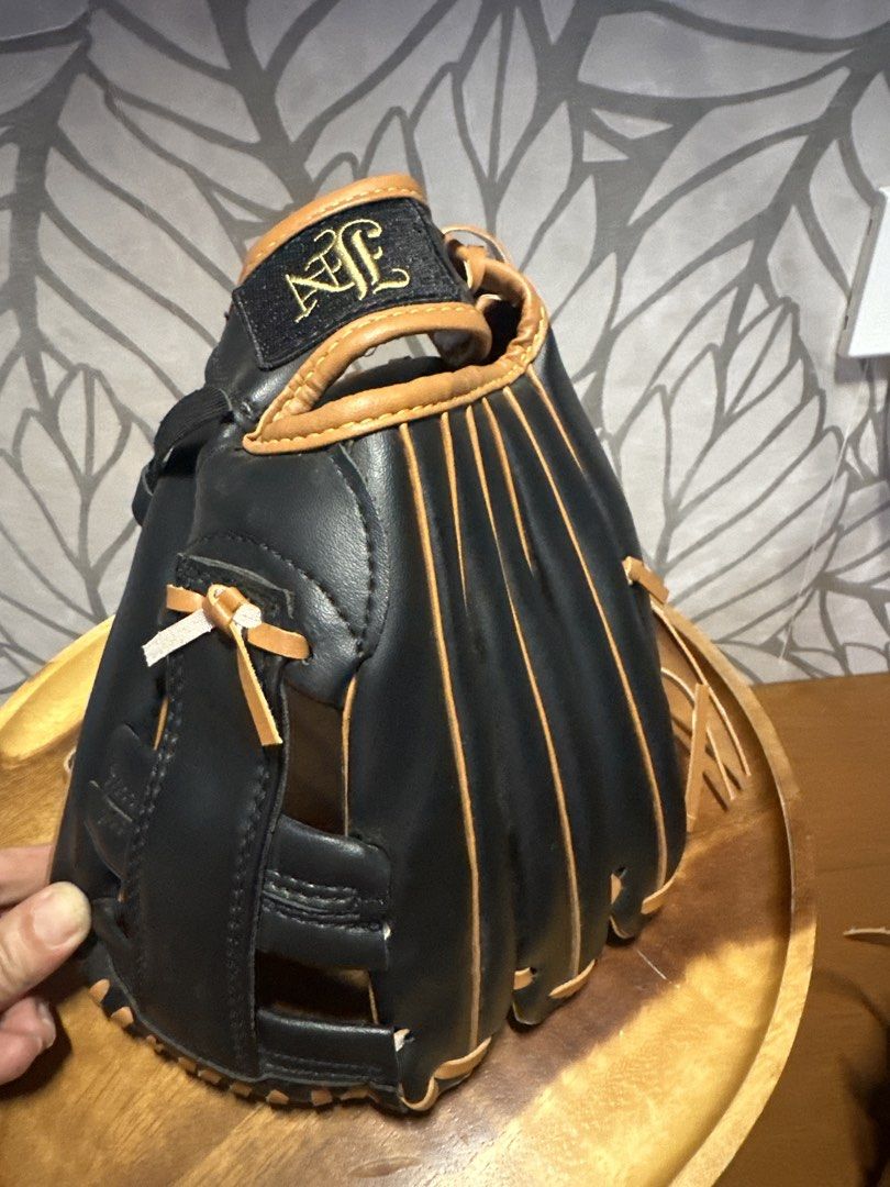 Black and Tan Handcrafted Nylon Stitched Baseball Glove (Category: Racket and Ball Sports) located in Makati City. Submitted by twodoxies (Listing ID 1466643270, Image 2). Description: Black leather baseball glove with tan lacing and piping accents. Hand crafted build featuring nylon stitched construction. Ornate interlocking logo stamped in gold on the palm and wrist strap. Webbed design with reinforced finger slots. Clean interior pocket with c