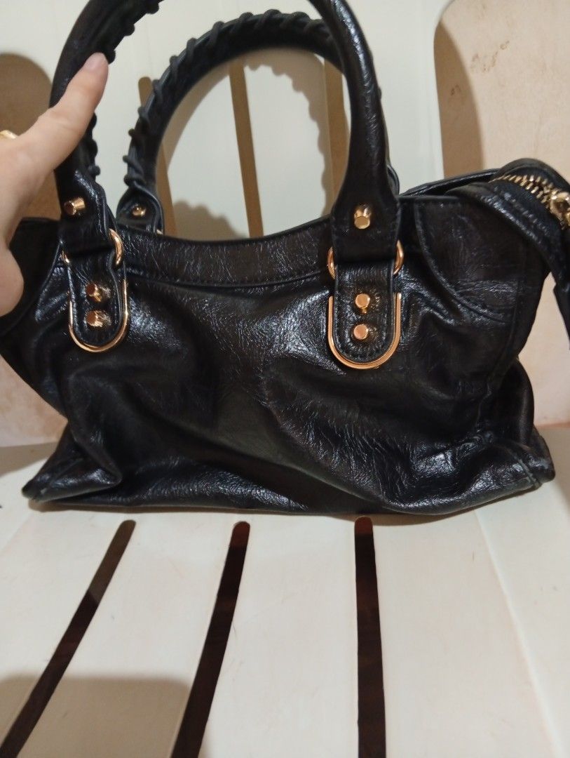 Black Leather Motorcycle Handbag with Gold Hardware (Category: Luxury Bags & Wallets) located in Cebu City. Submitted by champagnescloset (Listing ID 1466772237, Image 3). Description: Black leather handbag with a distinctive crinkled texture. Gold-tone hardware throughout, including studs, buckles, and zipper accents. Whipstitched twin handles on top, plus a front zip pocket and buckle detailing on the bottom corners. Zip closure across the top.