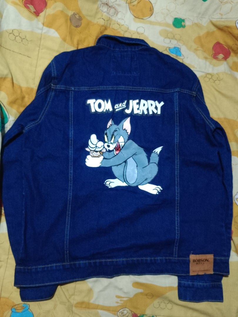 Bobson x Tom and Jerry Denim Jacket Size 2XL (Category: Coats, Jackets and Outerwear) located in Manila. Submitted by navias (Listing ID 1466638783, Image 3). Description: - Brand: Bobson - Condition: Brand new with original price tag attached, never worn - Size: 2XL - Color: Medium blue - Design: Tom and Jerry graphic print on the back, embroidery patches on the front chest and pockets - Closure: Button-up with metallic buttons.