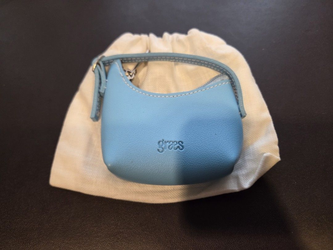 [Brand New] Graes Light Blue Coin Wallet (Category: Wallets & Card Holders) located in Manila. Submitted by liza1003 (Listing ID 1466625663, Image 1). Description: - Brand: Graes - Style: Mini wallet with top handle - Color: Light blue with white contrast stitching - Closure: Top zipper - Size: Mini / palm-sized - Inclusion: White cotton dust bag - Detail: Embossed brand logo on the front 24 hours reservation only No refunds, returns, or exchange