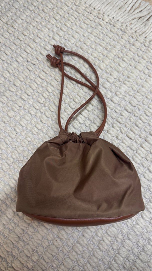 Brown Nylon Drawstring Purse (Category: Purses & Pouches) located in Paranaque City. Submitted by migvee (Listing ID 1466574961, Image 2). Description: - Color & Material: Brown nylon with a smooth leather base and matching leather straps - Closure: Drawstring top with stylish knotted string ends - Size: Compact and lightweight - Versatility: Neutral shade easily matches any casual outfit - Carry: Can be worn comfortably on the shoulder or carrie
