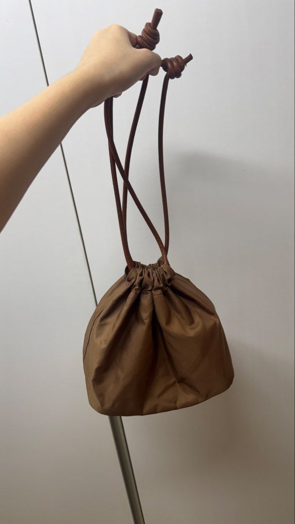 Brown Nylon Drawstring Purse (Category: Purses & Pouches) located in Paranaque City. Submitted by migvee (Listing ID 1466574961, Image 1). Description: - Color & Material: Brown nylon with a smooth leather base and matching leather straps - Closure: Drawstring top with stylish knotted string ends - Size: Compact and lightweight - Versatility: Neutral shade easily matches any casual outfit - Carry: Can be worn comfortably on the shoulder or carrie