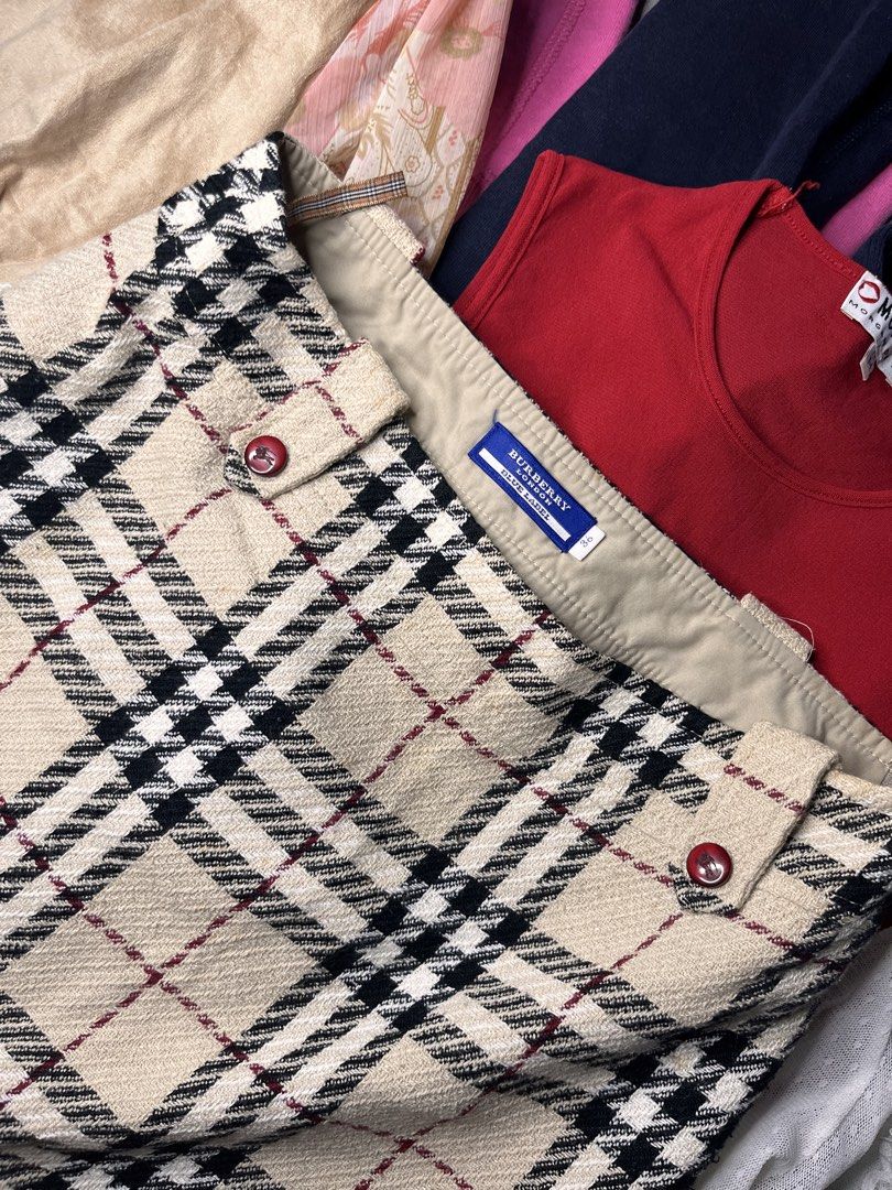 Burberry Blue Label Plaid Mini Skirt (Category: Skirts) located in Catbalogan. Submitted by yellfindss (Listing ID 1466755516, Image 2). Description: Burberry Blue Label mini skirt in classic beige check pattern. Black and red lines throughout. Structured wool-blend fabric with smooth lining inside. Side zipper closure. Branded red buttons on the waist tabs. Interior features signature Nova check hanging loops. Size 36 tag on the inner label. Y2K