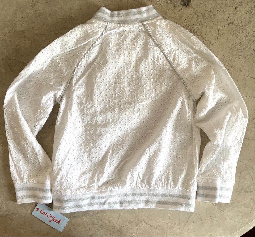 Cat & Jack White Eyelet Bomber Jacket (Category: Babies & Kids Fashion) located in San Juan City. Submitted by rike_ramirez (Listing ID 1466600562, Image 3). Description: Original and authentic, purchased in the USA Brand: Cat & Jack - Size: M (Ages 7/8) - Color: Fresh white with silver accents - Design: All-over eyelet embroidery with silver metallic ribbed collar, cuffs, and hem - Details: Chic silver piping along raglan sleeves and full front 