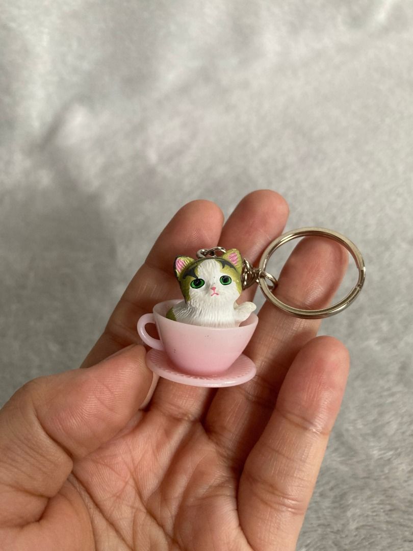 Cat in Pink Teacup Keychain (Category: Character Goods) located in Rizal. Submitted by sheeraay (Listing ID 1466650677, Image 1). Description: - Adorable calico kitten sitting inside a miniature pink teacup and saucer - Securely attached silver-toned keyring with a small chain - Versatile accessory for keys, purses, or backpacks - Compact and lightweight, fits easily in the palm of your hand - Brand new and ready to ship!.