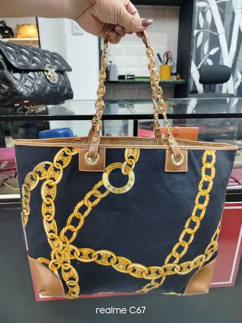 Celine Chain Print Canvas Tote Bag (Category: Luxury Bags & Wallets) located in Bacolod City. Submitted by Mike23MattPreloved (Listing ID 1466627420, Image 2). Description: - Brand: Celine - Material: Navy blue canvas with tan leather trim - Design: All-over gold chain print with sign of use with gold-tone hardware and engraved motifs - Features: Spacious interior, sturdy top handles - Condition: Good, with minor leather wear near handle attachme