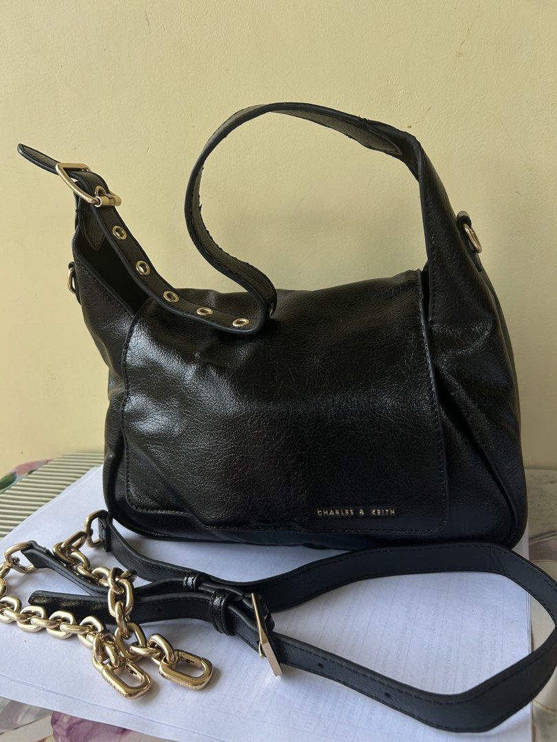 Charles & Keith Black Shoulder Bag with Chain Strap (Category: Shoulder Bags) located in Valencia. Submitted by carmzfindsph (Listing ID 1466684181, Image 1). Description: - Brand: Charles & Keith - Material: Black crinkled faux leather with gold-tone hardware - Closure: Flap with magnetic snap - Handles: Short top handle with gold eyelet details and adjustable buckle - Straps: Includes a removable long strap with a trendy chunky gold chain secti