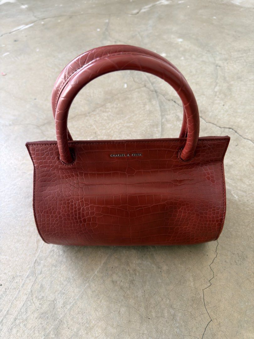 Charles & Keith Red Croc Handbag (Category: Luxury Bags & Wallets) located in Alfonso. Submitted by jbcamet (Listing ID 1466566603, Image 1). Description: - Brand: Charles & Keith - Color: Rich red - Material: Faux crocodile skin texture - Design: Structured rectangular shape with rounded top handles - Hardware: Silver-toned metal branding and protective metal feet at the base - Size: Compact, ideal for daily essentials.