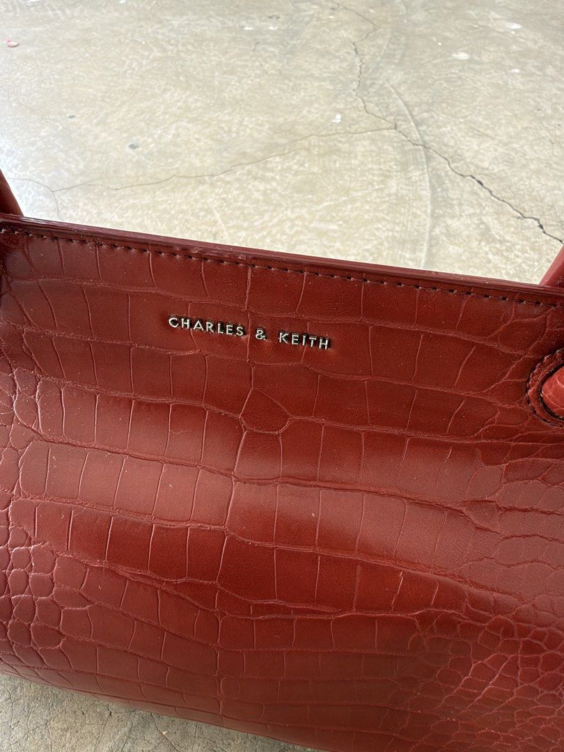 Charles & Keith Red Croc Handbag (Category: Luxury Bags & Wallets) located in Alfonso. Submitted by jbcamet (Listing ID 1466566603, Image 2). Description: - Brand: Charles & Keith - Color: Rich red - Material: Faux crocodile skin texture - Design: Structured rectangular shape with rounded top handles - Hardware: Silver-toned metal branding and protective metal feet at the base - Size: Compact, ideal for daily essentials.