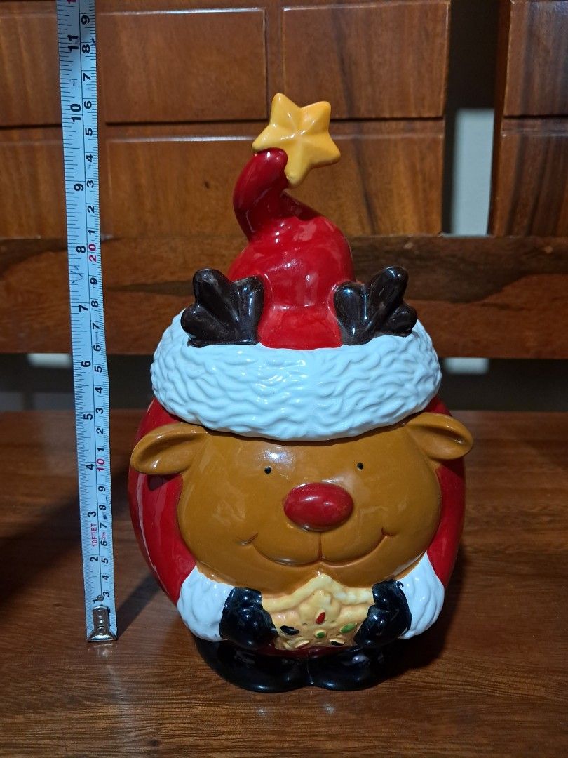 Christmas Elegance Reindeer Ceramic Cookie Jar with Box (Category: Food Organization & Storage) located in Makati City. Submitted by Titan (Listing ID 1466631074, Image 2). Description: - Adorable ceramic reindeer cookie jar wearing a festive Santa hat - Holds holiday cookies, treats, and candies - Measures approx. 11 inches tall from base to star tip - Features hand-painted details including a red nose, black mittens, and a star cookie - Comes w
