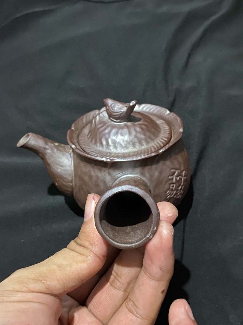 Vintage Clay Teapot With Side Handle And Carved Design (Category: Coffee & Tea Tableware) located in Marikina City. Submitted by jvdshop (Listing ID 1466672885, Image 3). Description: - Authentic brown clay teapot with a traditional side handle - Textured body featuring carved Chinese characters and an intricate wheel motif - Includes a matching lid topped with an adorable, sculpted bird - Perfect for brewing loose leaf tea or adding to a traditi