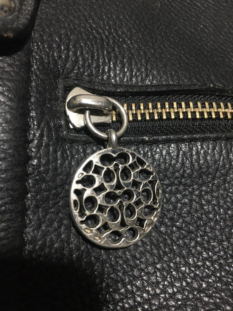 Coach Black Leather Shoulder Bag (Category: Luxury Bags & Wallets) located in Manila. Submitted by findingtreasure. (Listing ID 1466718820, Image 3). Description: Coach black pebble leather shoulder bag. Includes top handles plus an adjustable and removable strap. Exterior features a zip pocket with a decorative signature medallion charm. Zip-top closure opens to a vibrant purple satin lining with an interior creed patch stamped F17566. Silver-to
