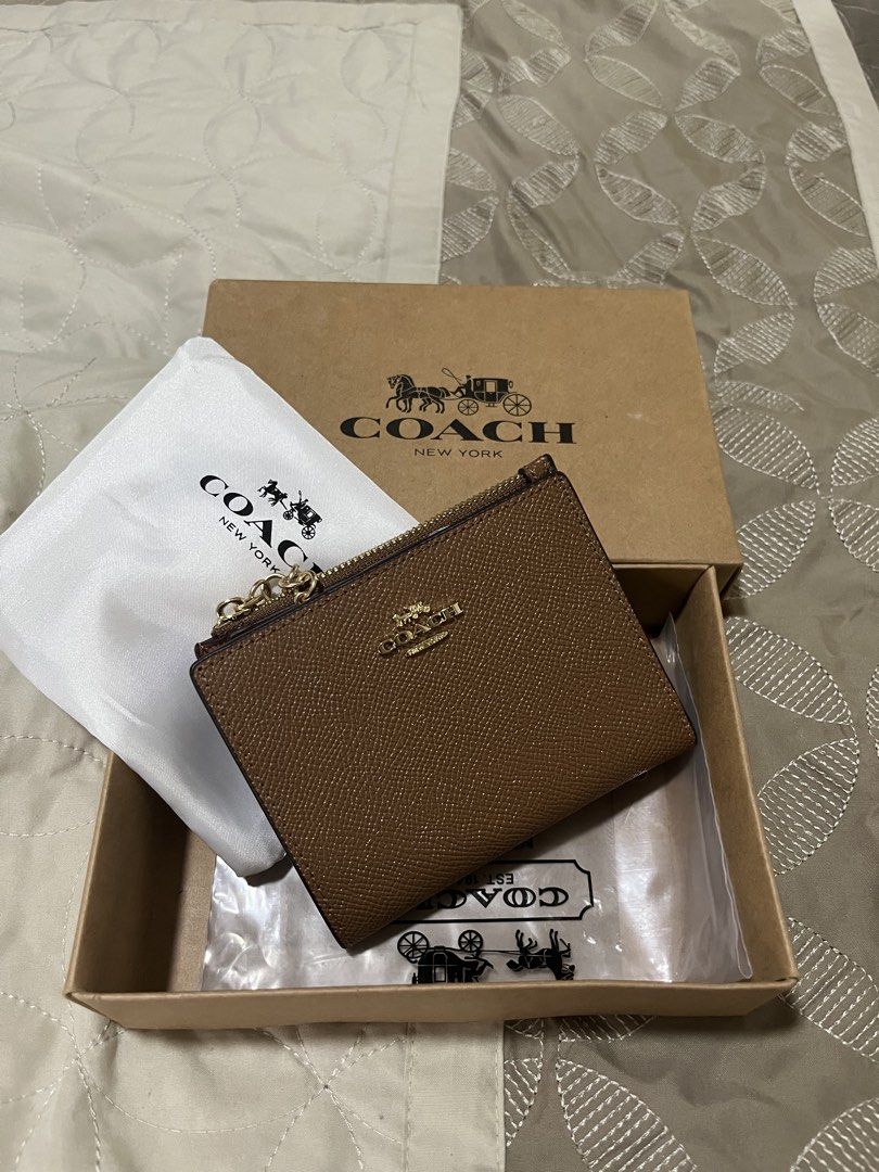 Coach Brown Leather Zip Small Wallet (Category: Wallets & Card holders) located in Quezon City. Submitted by eloveshopping.ph (Listing ID 1466596355, Image 1). Description: - Coach brown textured finish leather wallet with elegant gold-tone hardware - Secure snap closure and exterior zip pocket - Interior includes multiple card slots and a clear ID window - Made in Vietnam - Includes original box and dust bag - Condition: Excellent/Like New - Sel