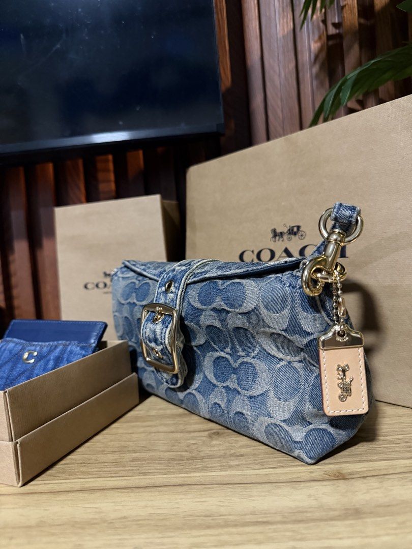 Coach Denim Signature Shoulder Bag (Category: Luxury Bags & Wallets) located in Taguig. Submitted by JHOs.it.up (Listing ID 1466589056, Image 2). Description: - Authentic Coach shoulder bag - Classic blue signature denim monogram print with leather charm - Elegant gold-tone hardware and chic front buckle detail - Structured rectangular shape for everyday use - Complete with tag, and paperbag - Condition: Brand new.