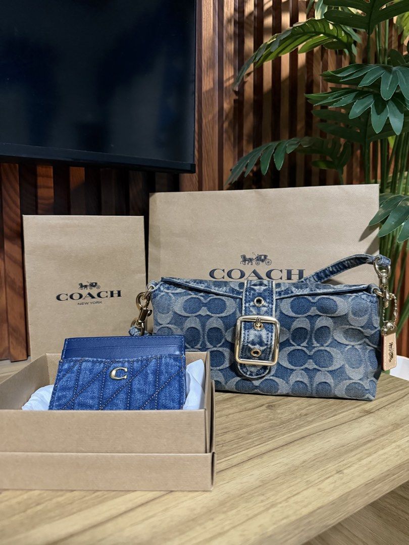 Coach Denim Signature Shoulder Bag (Category: Luxury Bags & Wallets) located in Taguig. Submitted by JHOs.it.up (Listing ID 1466589056, Image 1). Description: - Authentic Coach shoulder bag - Classic blue signature denim monogram print with leather charm - Elegant gold-tone hardware and chic front buckle detail - Structured rectangular shape for everyday use - Complete with tag, and paperbag - Condition: Brand new.