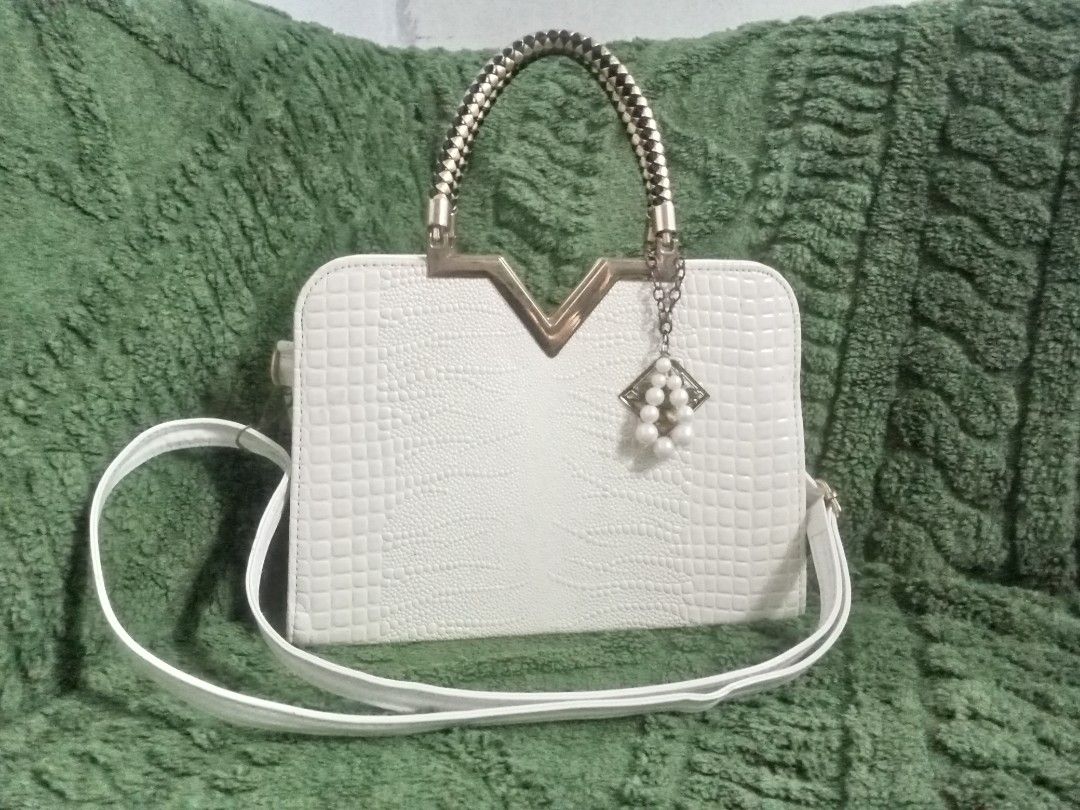 Crocodile Bag (Category: Tote Bags) located in Manila. Submitted by swiftdolphin_f17535 (Listing ID 1466611492, Image 1). Description: It is a white crocodile-textured top-handle square bag featuring a V-shaped gold accent on the front and a pearl-beaded charm. Ask a follow-up.