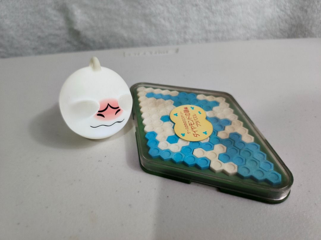 Diamond Puzzle Game and Squishy Toy Bundle (Category: Board Games & Puzzles) located in San Leonardo. Submitted by burgossanleonardo.12345 (Listing ID 1466692918, Image 3). Description: - Bundle Set: Includes a diamond puzzle game and a cute squishy toy - Diamond Puzzle: Blue and white hexagonal pieces in a clear plastic case, great fun brain teaser - Stress Toy: Adorable round white dumpling character with a flushed face and squiggly mouth - Con