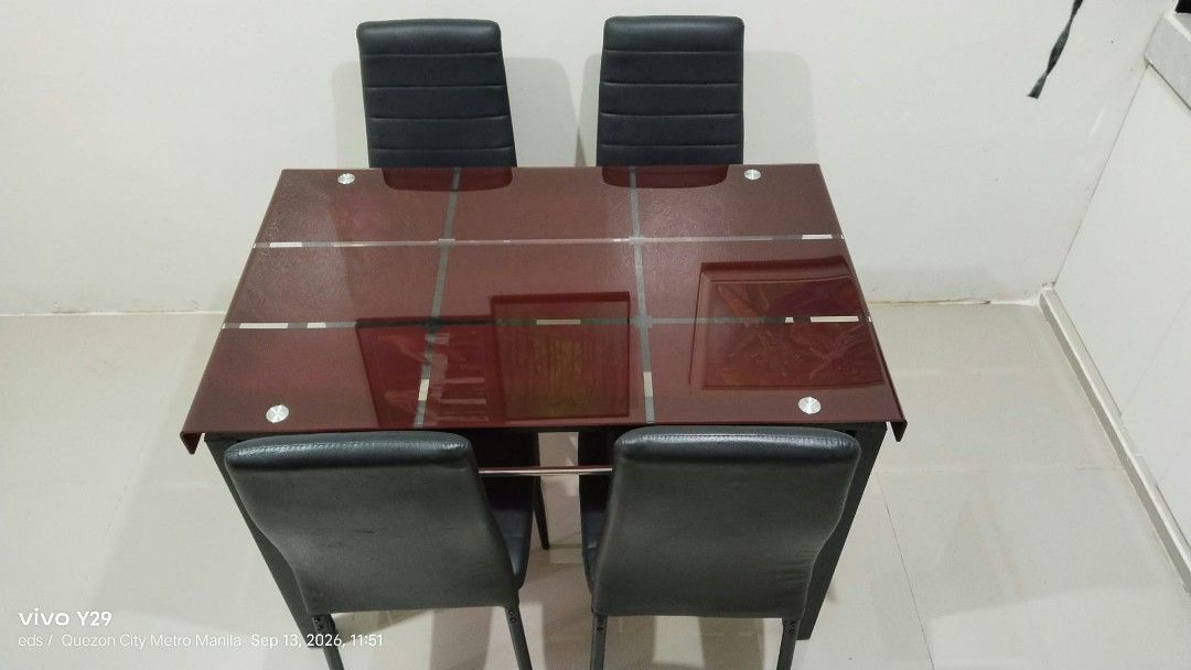 Dining table and 4 chairs set (Category: Tables & Sets) located in Quezon City. Submitted by kaoriagathas (Listing ID 1466616572, Image 2). Description: - Modern dining set with reddish-brown glass top and sturdy black metal legs - Includes 4 matching black upholstered chairs featuring stylish horizontal channel tufting - Compact design, fits small dining spaces and kitchens nicely - Neutral tones easily match most home interiors - Ready for pick