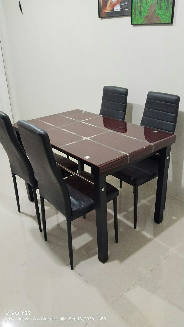 Dining table and 4 chairs set (Category: Tables & Sets) located in Quezon City. Submitted by kaoriagathas (Listing ID 1466616572, Image 1). Description: - Modern dining set with reddish-brown glass top and sturdy black metal legs - Includes 4 matching black upholstered chairs featuring stylish horizontal channel tufting - Compact design, fits small dining spaces and kitchens nicely - Neutral tones easily match most home interiors - Ready for pick