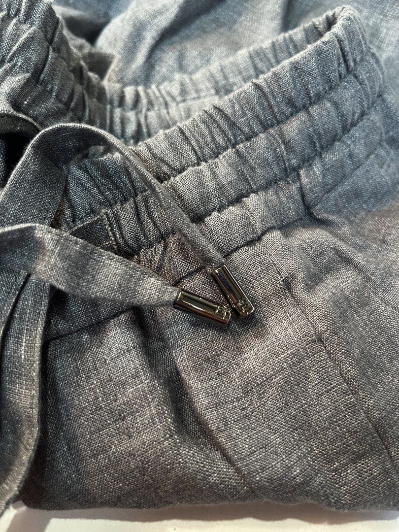 Dolce & Gabbana Grey Linen Drawstring Pants Size 44 (Category: Trousers) located in Dumangas. Submitted by duerocharl67867 (Listing ID 1466567473, Image 3). Description: - Brand: Dolce & Gabbana - Color: Grey - Size: 44 (Tag attached) - Material: 100% Linen (Made in Italy) - Waistband: Elastic with drawstring closure and branded metallic aglets - Pockets: Dual rear welt pockets with button closures - Details: Signature embroidered DG logo on the 
