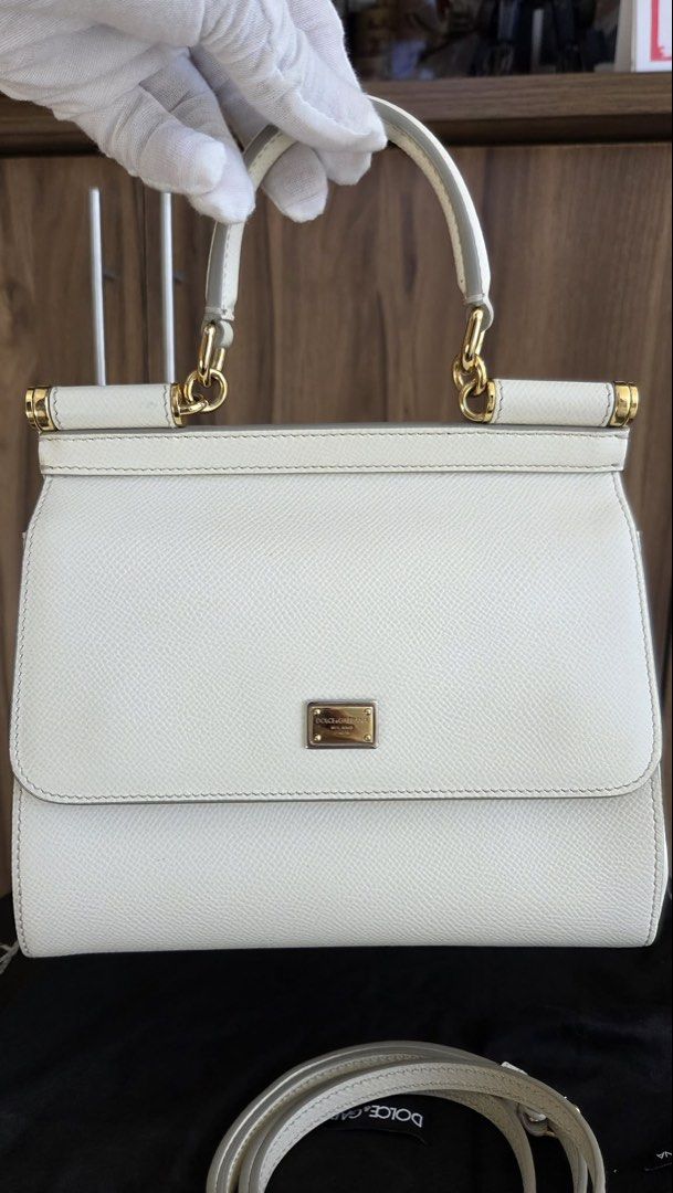 Dolce & Gabbana White Sicily Handbag (Category: Luxury Bags & Wallets) located in Rizal. Submitted by bearbricksmum (Listing ID 1466772295, Image 2). Description: White Dolce & Gabbana top handle bag. Textured leather body with gold-tone hardware and metal logo plaque on the front. Includes a detachable matching shoulder strap and dust bag. Structured shape with a single top handle and flap closure. Clean interior and exterior, ready to carry. Pi
