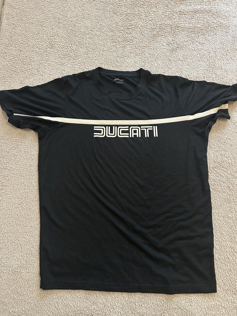 Ducati Alice Black T-Shirt Size L (Category: Tshirts & Polo Shirts ) located in Quezon City. Submitted by mancave_stuff (Listing ID 1466567366, Image 1). Description: - Brand: Ducati - Color: Black with beige stripe/logo chest - Size: Large (L) W20” x L27” - Material: 95% Pima Cotton, 5% Spandex (soft with great stretch) - Design: Contrasting chest stripe with bold Ducati lettering, plus back graphic featuring Ducati text and an Alice logo inside