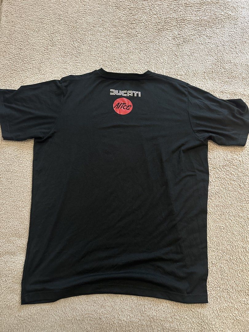 Ducati Alice Black T-Shirt Size L (Category: Tshirts & Polo Shirts ) located in Quezon City. Submitted by mancave_stuff (Listing ID 1466567366, Image 2). Description: - Brand: Ducati - Color: Black with beige stripe/logo chest - Size: Large (L) W20” x L27” - Material: 95% Pima Cotton, 5% Spandex (soft with great stretch) - Design: Contrasting chest stripe with bold Ducati lettering, plus back graphic featuring Ducati text and an Alice logo inside