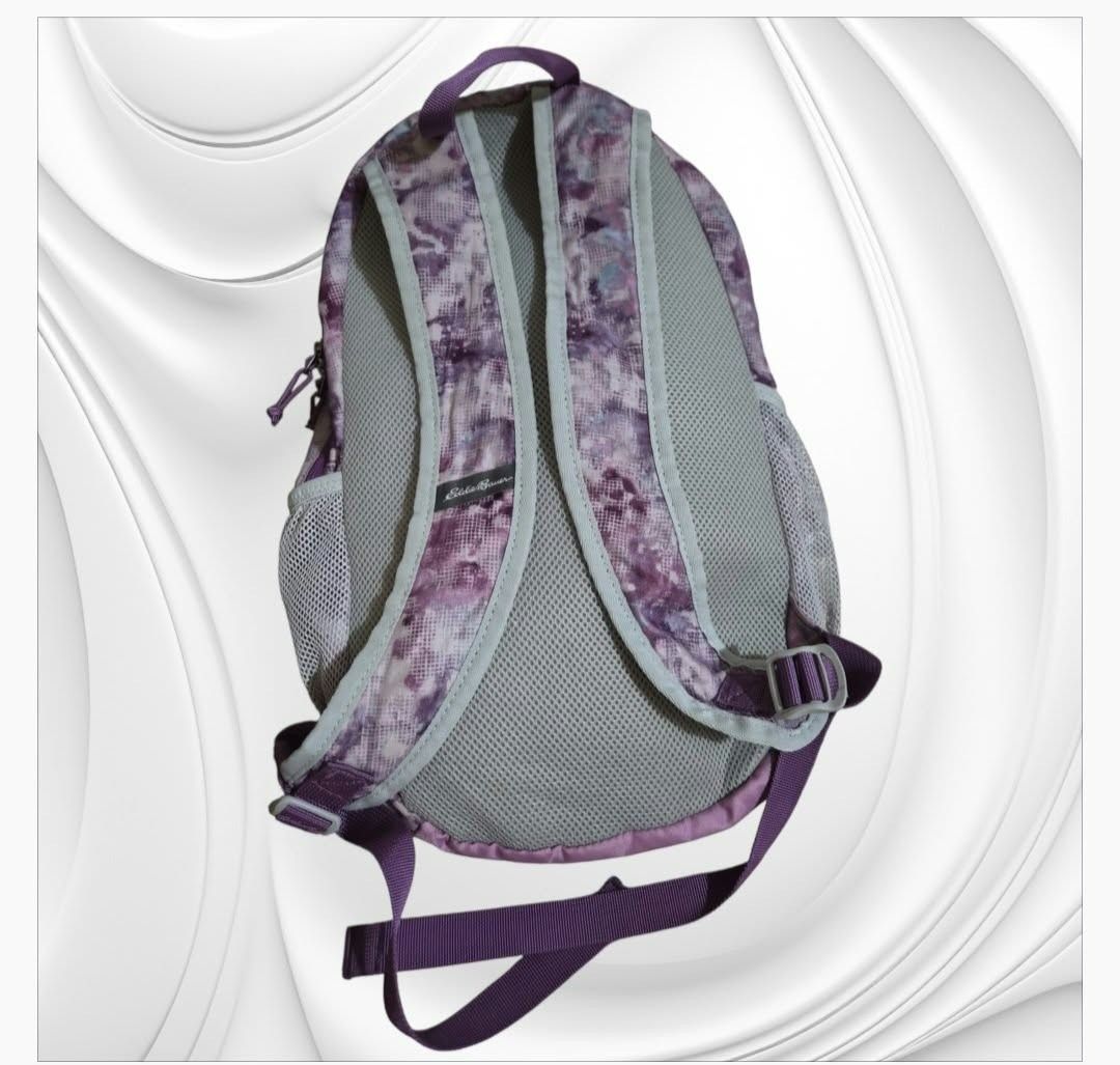 Eddie Bauer 20L Purple Pattern Backpack (Category: Backpacks) located in Paranaque City. Submitted by calm_youngstore7 (Listing ID 1466724313, Image 2). Description: - Brand: Eddie Bauer - Capacity: 20L - Design: Pink and purple patterned - Condition: Brand new with tags still attached - Compartments: Main zippered compartment, front vertical zip pocket, and mesh side pockets - Comfort: Padded mesh shoulder straps, back panel, and top grab handle