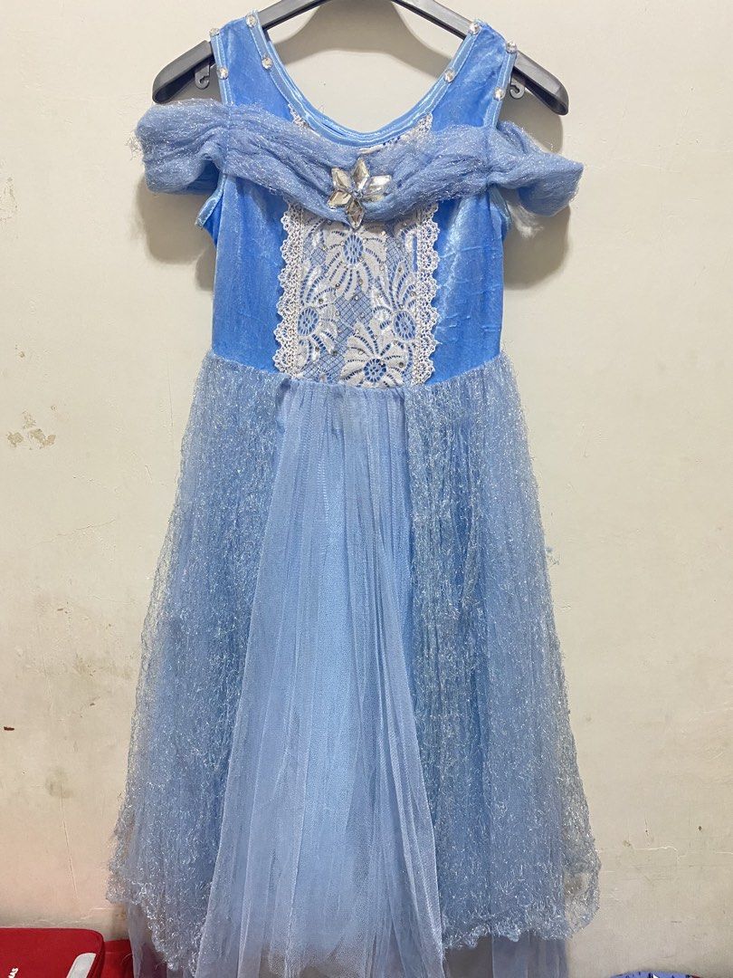 Elsa Inspired Dress (Category: Babies & Kids Fashion) located in Las Pinas. Submitted by dhyn29 (Listing ID 1466677279, Image 1). Description: - Light blue princess costume dress with blue velvet-like upper body - Off-the-shoulder draped sleeves and white lace bodice panel - Large silver gem brooch attached at the neckline - Sparkly silver textured tulle overlay on the skirt - Condition note: One strap has a torn seam near the arm opening which r