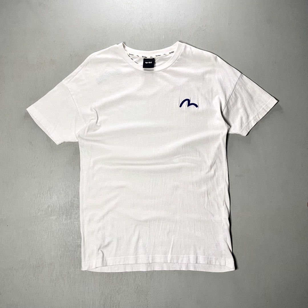 Evisu White Graphic T-Shirt (Category: Tshirts & Polo Shirts ) located in Catbalogan. Submitted by yellfindss (Listing ID 1466745457, Image 3). Description: - Brand: Evisu -18/27 - Color: White - Style: Short sleeve crew neck tee - Details: Embroidered blue seagull logo on left chest - Back Design: Multicolored printed typography across the shoulders - Interior: Branded taping inside the collar - Condition: Clean overall.
