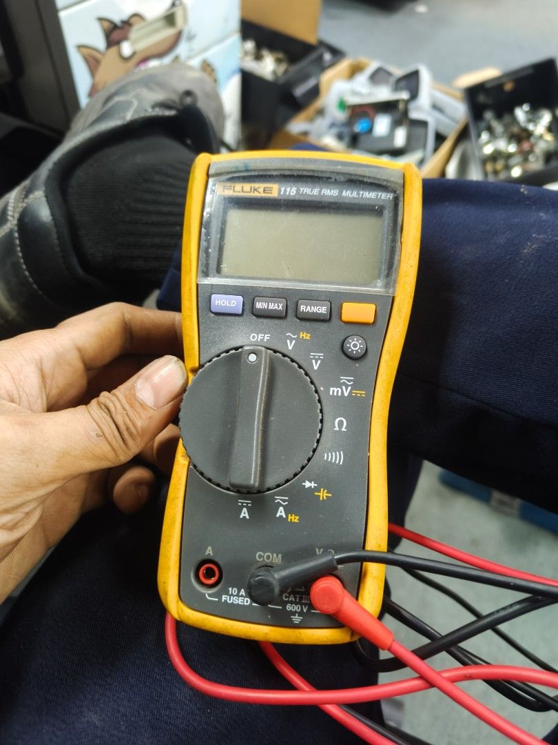 Fluke 115 True RMS Multimeter (Category: Construction Tools & Equipment) located in Taguig. Submitted by martin1990easy (Listing ID 1466703287, Image 3). Description: - Model: Fluke 115 Digital Multimeter - Condition: Used with minor workspace scuffs and dust; fully functional - Included Accessories: Original yellow protective rubber holster, black test lead, and red test lead - Features: Standard center rotary dial, top digital screen, Hold, Min