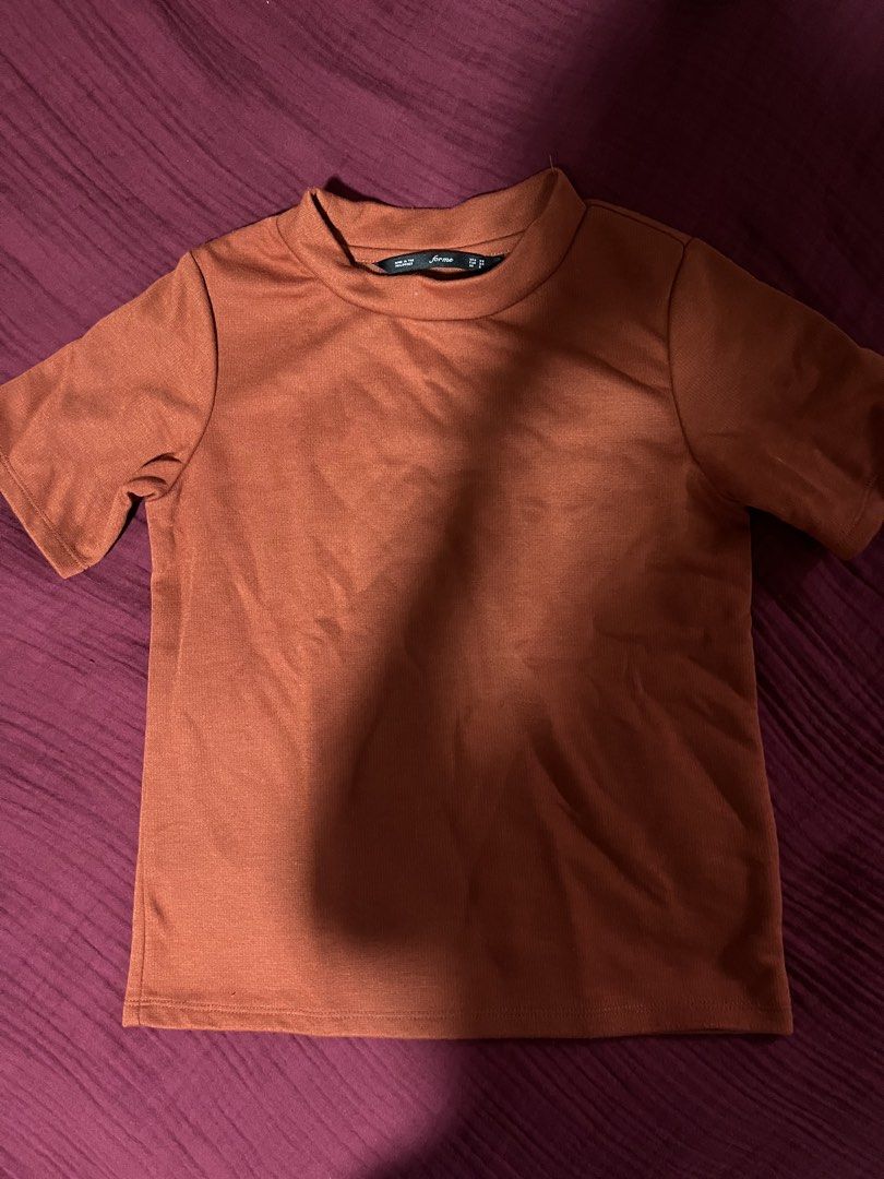 Forme Rust Orange Mock Neck Short Sleeve Top (Category: Shirts) located in Manila. Submitted by new.gabrielle (Listing ID 1466649207, Image 1). Description: - Brand: Forme - Color: Rust orange - Style: Mock neck, short sleeve, standard fit - Fabric: Clean, solid color - Versatility: Easy to pair with jeans or skirts for daily wear - Details: Size tag clearly shown at the collar.
