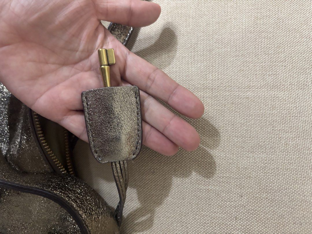 Fossil Metallic Bronze Leather Shoulder Bag (Category: Shoulder Bags) located in Famy. Submitted by frenchmacaroon (Listing ID 1466581498, Image 3). Description: - Brand: Fossil - Color: Metallic bronze with a subtle shiny finish - Material: Genuine leather with brass hardware - Closure: Secure zip-top closure - Features: Includes a detachable/adjustable long strap and signature Fossil key charm - Storage: Roomy interior, great size for daily ess