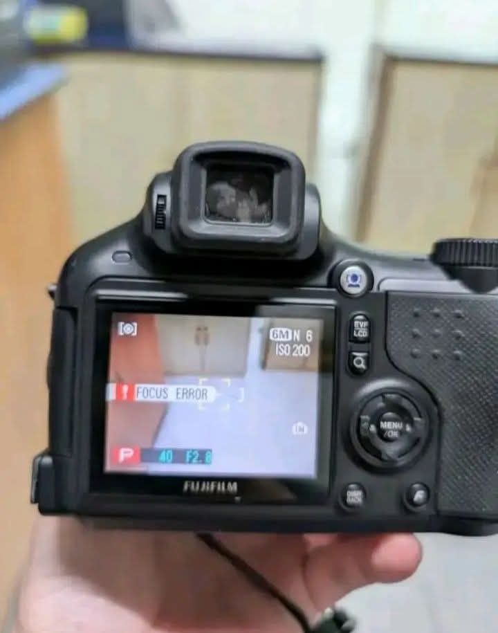 Fujifilm FinePix Digital Camera (Category: Cameras) located in Manila. Submitted by newshark.e01180 (Listing ID 1466710529, Image 2). Description: - Brand: Fujifilm digital camera - Lens: Fujinon zoom lens with 10.7x optical zoom (6.2-66.7mm focal length, f/2.8-4.9 aperture) - Inclusions: Original lens cap with attached string - Condition: Body shows standard signs of handling; screen displays a focus error message during operation - Ideal for: C
