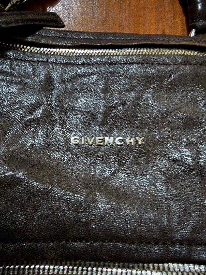 Givenchy pandora (Category: Luxury Bags & Wallets) located in Manila. Submitted by izzycollections (Listing ID 1466595538, Image 2). Description: Dark brown leather Givenchy bag with silver-toned hardware and multiple exterior zipper compartments. Double top handles plus a detachable shoulder strap. Visible wear and scuffing on the leather corners and edges, adding a vintage distressed look. Fabric lining and structured silhouette. Classic design