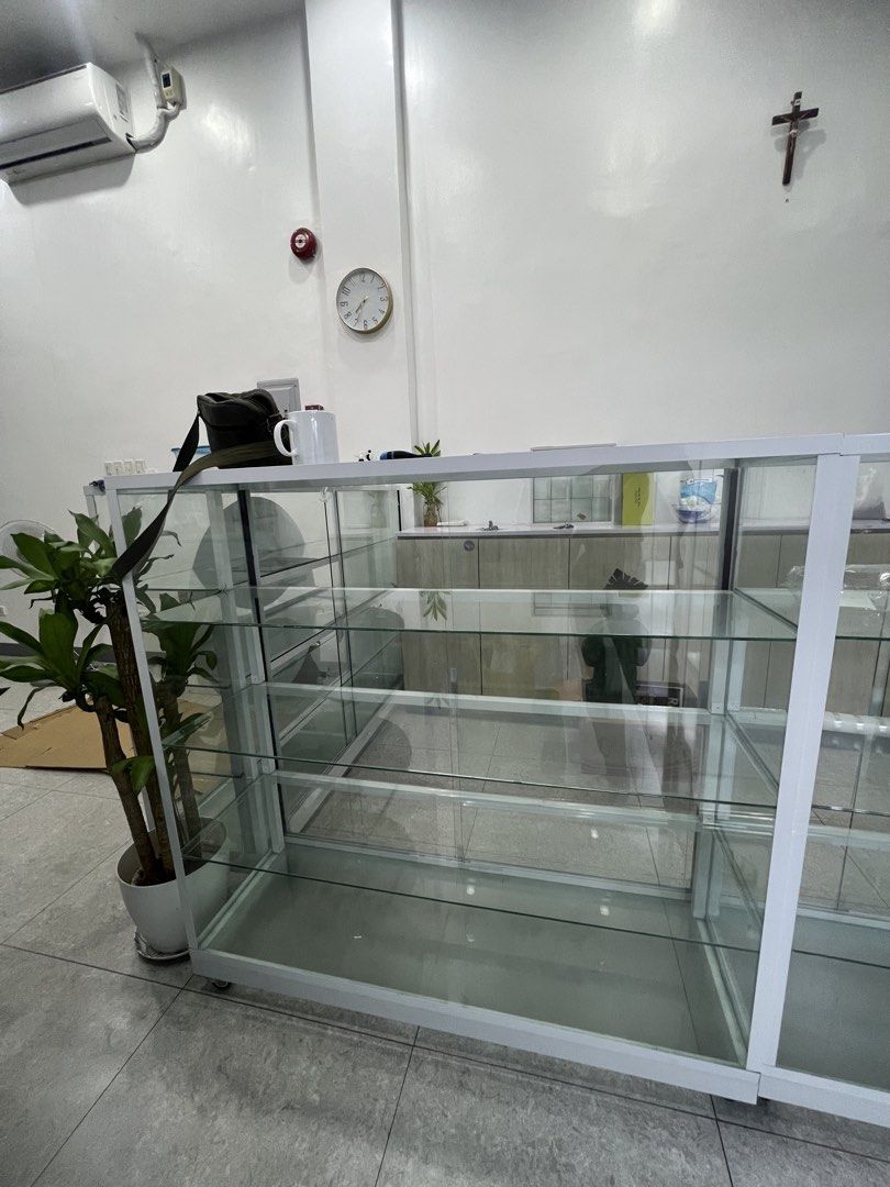 Glass Display Cabinet Showcase Retail Counter (Category: Shelves, Cabinets & Racks) located in Pasay City. Submitted by katkat143 (Listing ID 1466744624, Image 2). Description: - Color/Frame: Clean white frame with clear glass panels - Storage: Multiple tiers of glass shelves - Mobility: Equipped with wheels for easy moving - Ideal Use: Perfect for retail shops or displaying collectibles - Condition/Note: Sturdy build; pick up only.