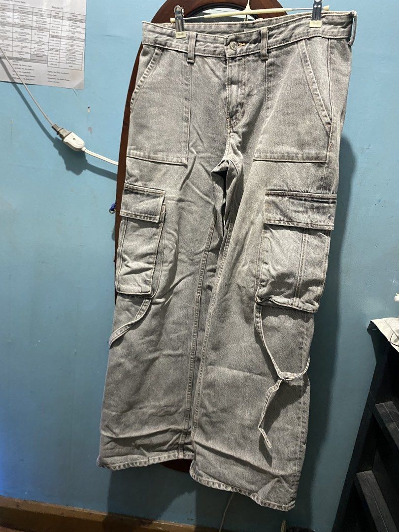 Grey denim cargo pants with multiple pockets (Category: Jeans) located in Manila. Submitted by mimi_goods.ph (Listing ID 1466598884, Image 1). Description: - Style: Grey denim cargo pants with a trendy wide-leg fit - Storage: Functional utility pockets on both sides - Custom Fit: Adjustable drawstrings at the lower hems - Waistline: Secure button closure with belt loops - Material: Premium heavy cotton - Condition: Worn a few times, no stains or 