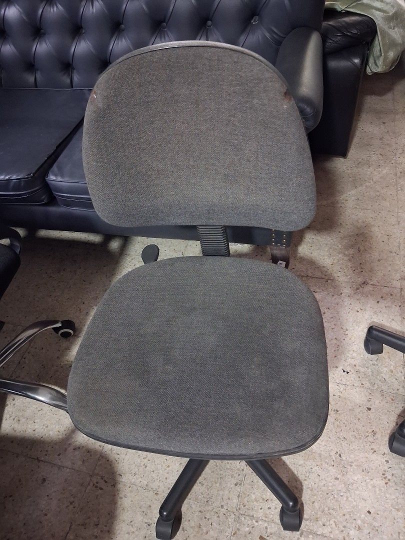 Grey rolling office chair with wheels (Category: Office Furniture & Fixtures) located in Quezon City. Submitted by ssvcn (Listing ID 1466602767, Image 1). Description: - Color: Grey - Material: Fabric upholstery on seat and backrest with a sturdy metal star base - Mobility: Rolling casters for easy movement - Adjustability: Height-adjustable gas lift mechanism - Condition: Fully functional and sturdy, with minor stains visible on the backrest fab